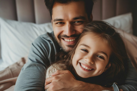 Latin man and his little daughter hugging in bedroomの素材
