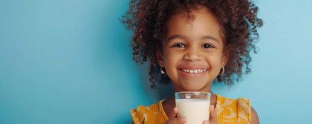 Happy African American little girl with glass of milk isolated on blue backgroundの素材