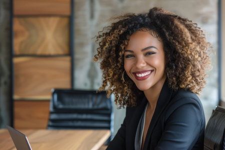 A joyful businesswoman smiles brightly in the boardroom of an office, accompanied by her laptop.の素材