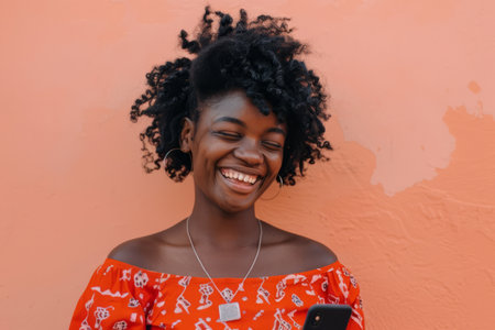 An African-American woman smiles confidently as she recommends a vibrant mobile app on a peach background, her positive energy captivating.の素材