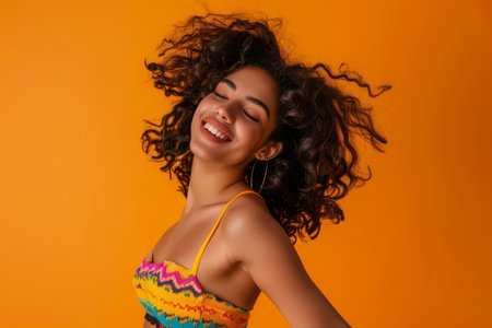 A lively Latina woman dances joyfully to music with bright, cheerful moves against an orange backdrop.の素材