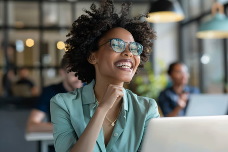 A euphoric businesswoman displays a big smile in the office boardroom, her laptop serving as a valuable tool for productivity.の素材
