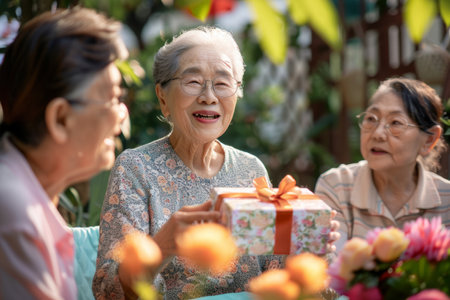 Celebrating the senior lady's birthday in the garden with family, where she is joyfully receiving a gift.の素材