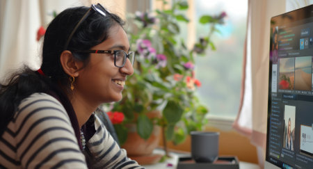 A joyful Indian woman, balancing remote work or teaching, takes part in a virtual conference meeting or online English class, attending an e-learning webinar on her computer from the comfort of her home.の素材