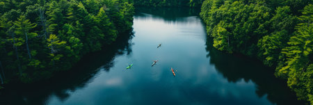 a drone view of a serene lake surrounded by dense forest with kayakers enjoying the waterの素材