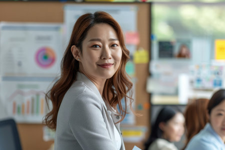 a Korean businesswoman planning a marketing strategy with colleagues in a bright officeの素材