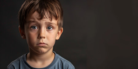 a Caucasian boy expressing sadness on a studio backgroundの素材