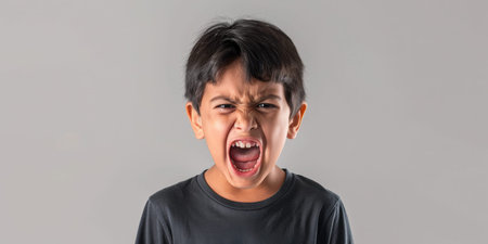 a Hispanic boy expressing anger on a studio backgroundの素材