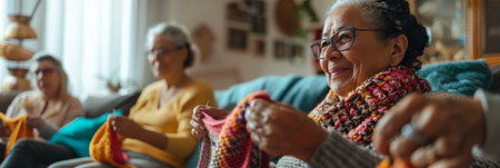 a Hispanic retired woman knitting with friends in a cozy living roomの素材
