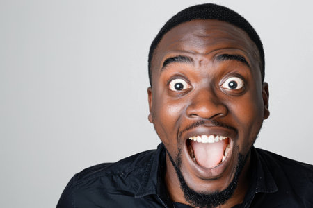 an African American man showing surprise on a studio backgroundの素材