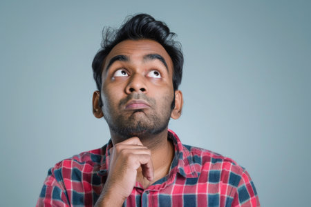 an Indian man looking thoughtful on a studio backgroundの素材