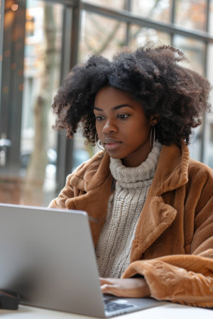 beautiful african american woman using laptop while sitting in cafeの素材