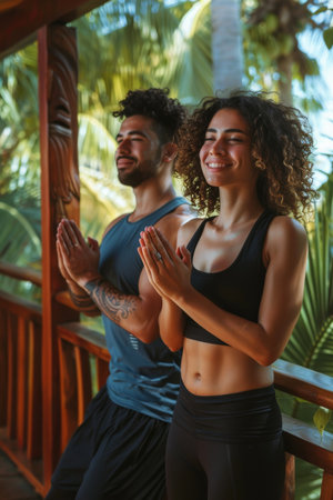 a Hispanic couple doing a quick yoga session together on their balconyの素材