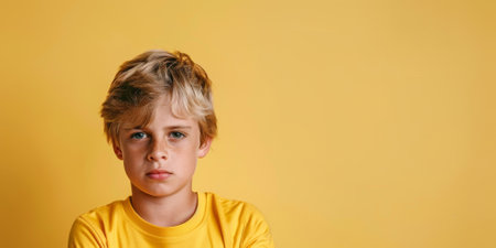 a Caucasian boy in a yellow football jersey, looking determined on a yellow studio backgroundの素材