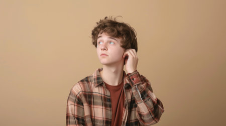 a Caucasian teenager looking anxious on a beige studio backgroundの素材