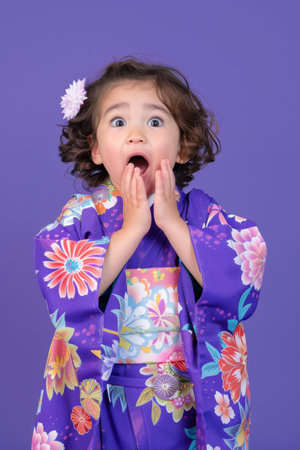 a Japanese child in a purple yukata, expressing surprise on a purple studio backgroundの素材