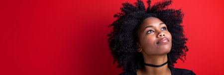 an African American woman looking hopeful on a red studio backgroundの素材