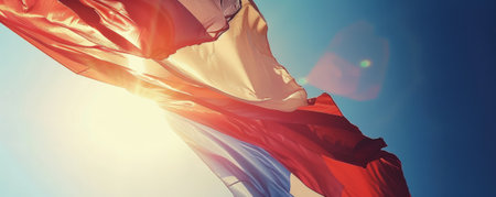 Bastille Day background with a close-up of a tricolor flag waving in the wind against a clear blue sky.の素材