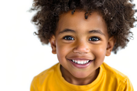 Cute African American preschool-aged boy with a charming smile, looking into the camera, isolated on white background.の素材