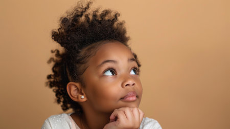 an African American girl showing curiosity on a beige studio backgroundの素材