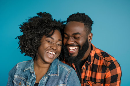 an African American couple laughing together on a blue studio backgroundの素材
