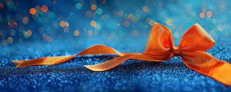 A bright orange ribbon bow on a blue glitter background. The contrasting colors and sparkling backdrop create a playful and energetic scene.の素材