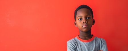 Unhappy school-age African American boy against a red background banner with copy space.ai generatedの素材