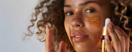 A young woman applying serum to her face while holding a bottle of dietary supplements for skin health. The image captures the seamless integration of supplements and skincare.の素材
