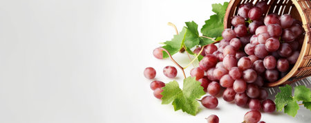 Fresh organic grapes spilling out of a wooden basket, with text space on a clean, white backdrop.の素材