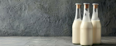 Trendy fermented dairy drinks with probiotics poured from glass bottles on a chic gray background. The neutral tone provides a sleek and sophisticated backdrop.の素材