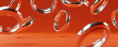 Silver rings floating in front of a pumpkin orange background, creating a striking and bold appearance.の素材