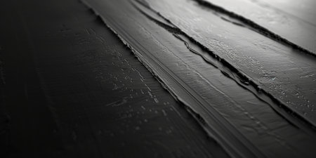 A dark black textured surface with a glossy, smooth finish that reflects light in a subtle, elegant manner. The sleek texture suggests modernity.の素材