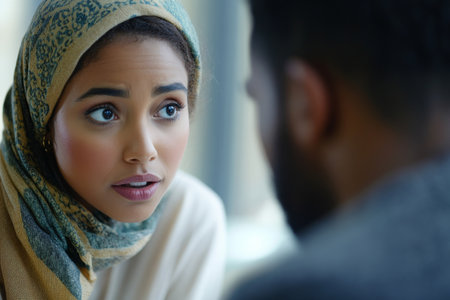 A close up view of an Arabian woman and a Black man in an interview setting, their expressions revealing engagement and curiosity. The blurred background highlights the importance of their discussion in a professional context.の素材