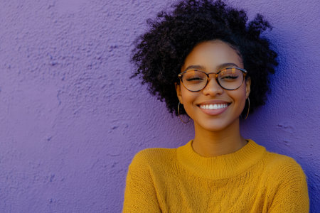Young African American woman with glasses, smiling confidently, lively expression, standing against a soft lavender background, exuding vibrant, positive energy.の素材