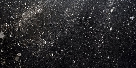 Dark granite surface with speckles in shades of gray and black, offering a sleek, polished stone lookの素材