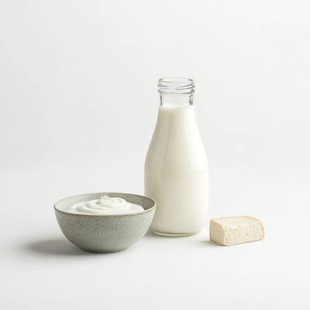A trio of dairy products including a bottle of milk, a bowl of yogurt, and a small piece of cheese, isolated on a white backgroundの素材