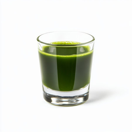 A small glass of fresh wheatgrass juice, isolated on a white background, emphasizing a nutrient-rich drinkの素材