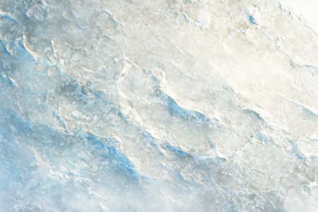 Textured snow surface, soft uneven layers with faint blue shadows and shimmering highlightsの素材