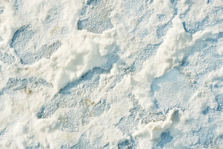 Textured snow surface, soft uneven layers with faint blue shadows and shimmering highlightsの素材