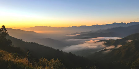 A dramatic mountain ridge at sunrise, with peaks glowing in shades of orange and pink, a sea of clouds in the valley below, and a solitary hiker taking in the view. The inspiring and majestic scene feels serene.の素材