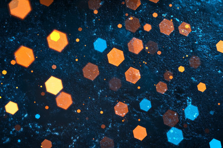 A vibrant background with scattered glowing hexagons in orange and blue over a textured dark surface.の素材