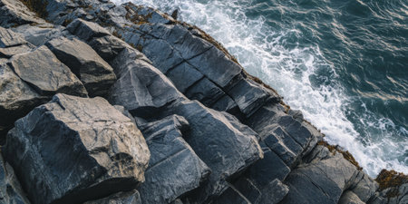 Ocean cliffside rock background with rugged, weathered gray stones shaped by crashing waves.の素材