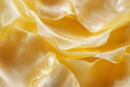 Macro shot of sunflower petal texture, silky, golden yellow surfaces with soft veins running through.の素材