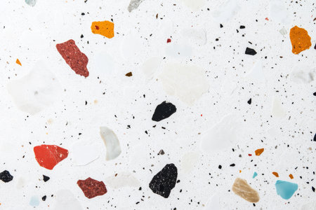 A minimalist terrazzo pattern with scattered colorful stone chips embedded in a white cement background.の素材
