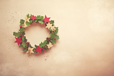 A charming Christmas wreath made from intricately cut paper, adorned with tiny stars and holly leaves on a textured kraft paper background.の素材