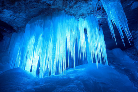 A breathtaking 3D background of an ice cave illuminated by glowing blue crystals. Jagged icicles hang from the ceiling, while frozen waterfalls glisten under the pale moonlight. The air is filled with the quiet echo of dripping water.の素材