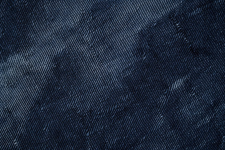 A distressed twill fabric texture background in faded navy blue. The diagonal weave pattern with subtle fraying and aged characteristics adds depth and character, perfect for vintage denim, workwear, and industrial aesthetics.の素材