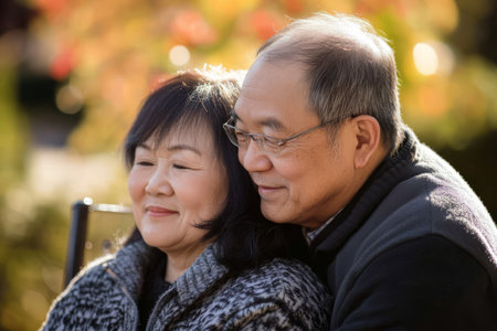 A husband gently tucking his wifeÃ¢â¬â¢s hair behind her ear as they sit together on a sunny afternoon.の素材