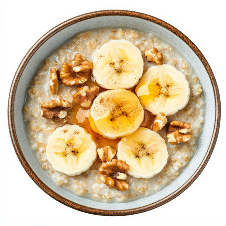 A bowl of hearty oatmeal topped with sliced bananas, chopped walnuts, a drizzle of honey, and a sprinkle of cinnamon. A wholesome and nourishing breakfast. Isolated on clean white backgroundの素材