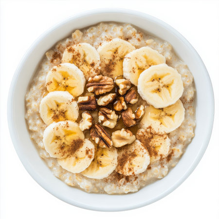 A bowl of hearty oatmeal topped with sliced bananas, chopped walnuts, a drizzle of honey, and a sprinkle of cinnamon. A wholesome and nourishing breakfast. Isolated on clean white backgroundの素材